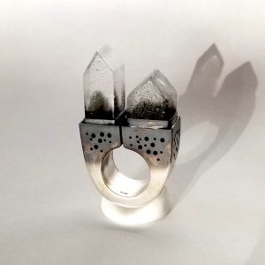 The American Dream: Fairbanks, AK is a hollow form statement ring made from silver. on the top are set two tiny glass houses