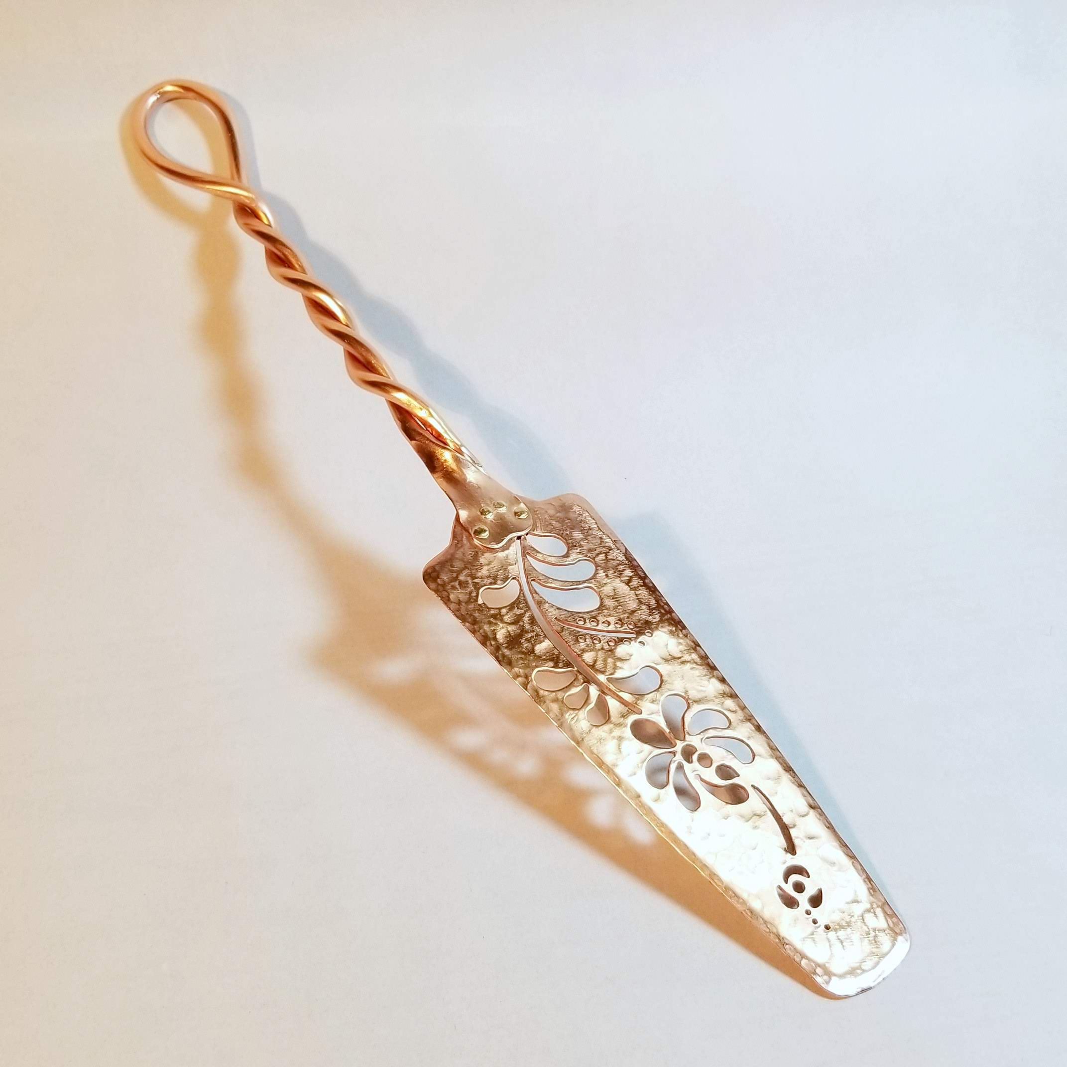 A copper cake server with pierced pattern
