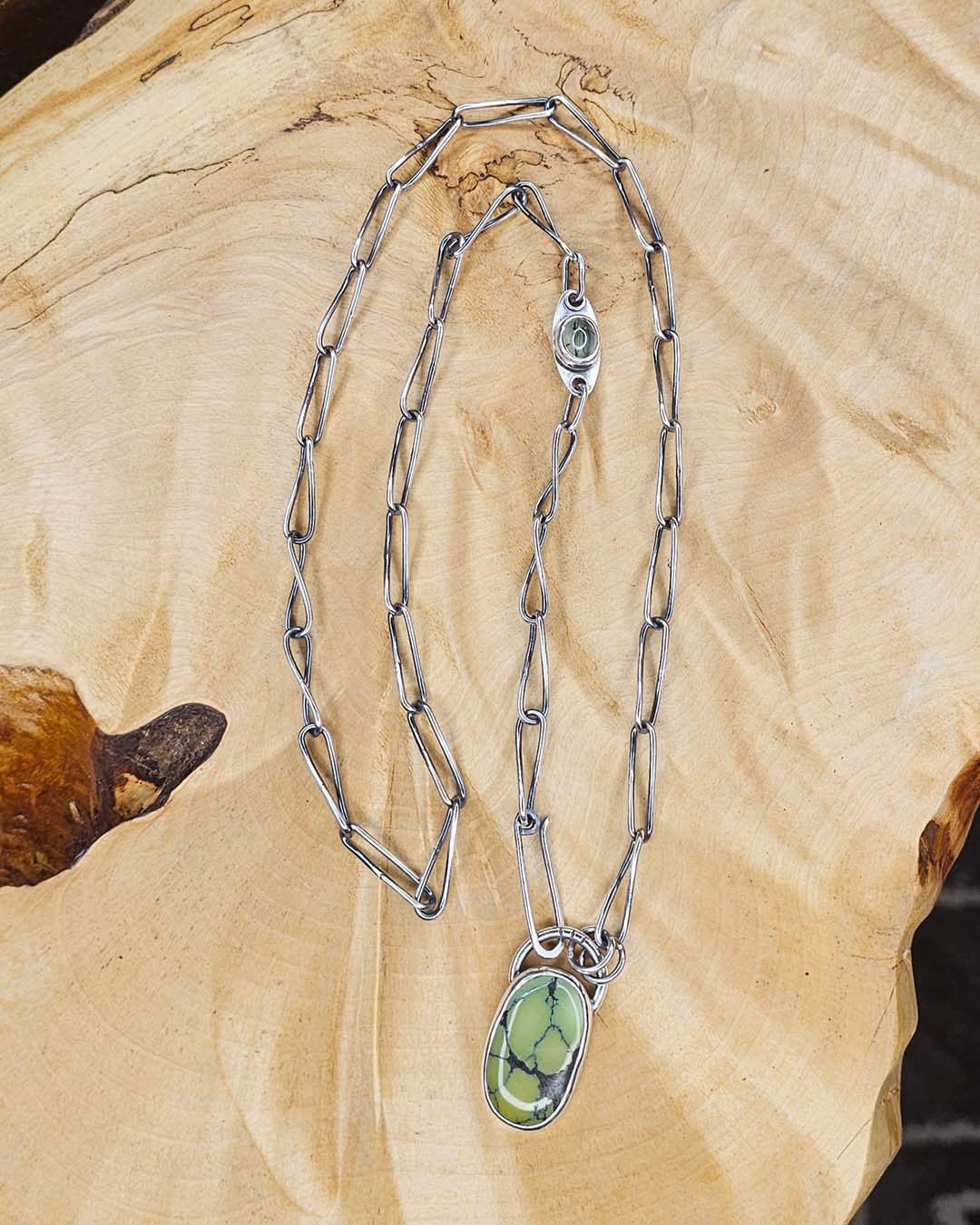 A green turquoise pendant on a handmade silver chain. A Prehenite cabochon is set in the chain to accent the green of the turquoise