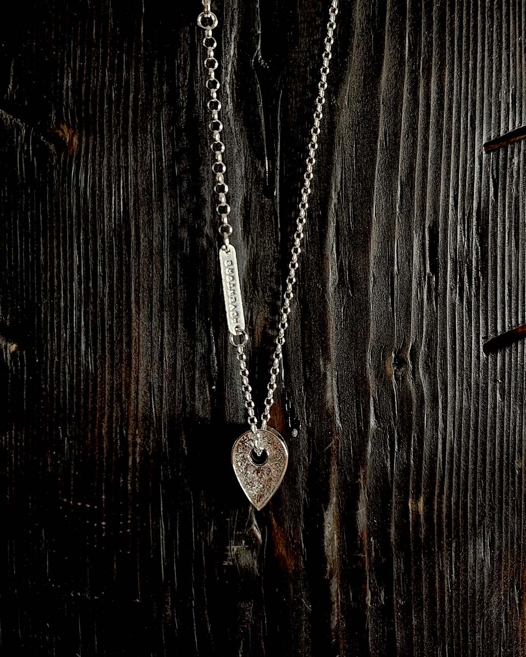 A necklace featuring a map marker planchette pendant made with reticulated silver and framed in a narrow sterling silver strip