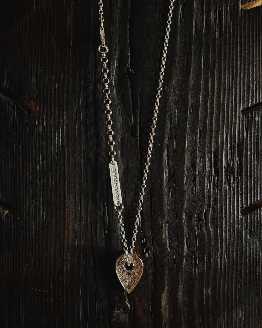 A necklace featuring a map marker planchette pendant made with reticulated silver and framed in a narrow sterling silver strip