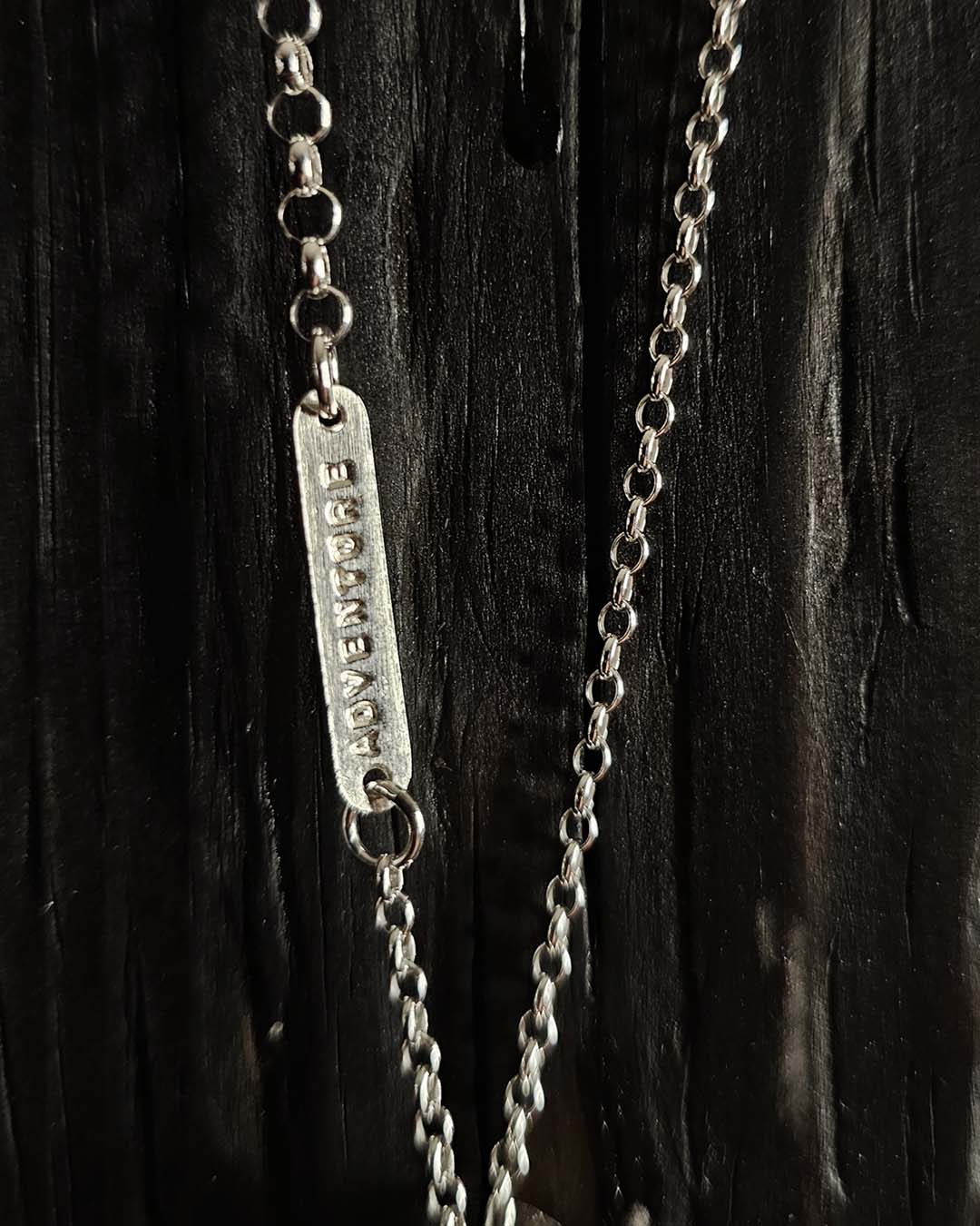 A necklace featuring a map marker planchette pendant made with reticulated silver and framed in a narrow sterling silver strip