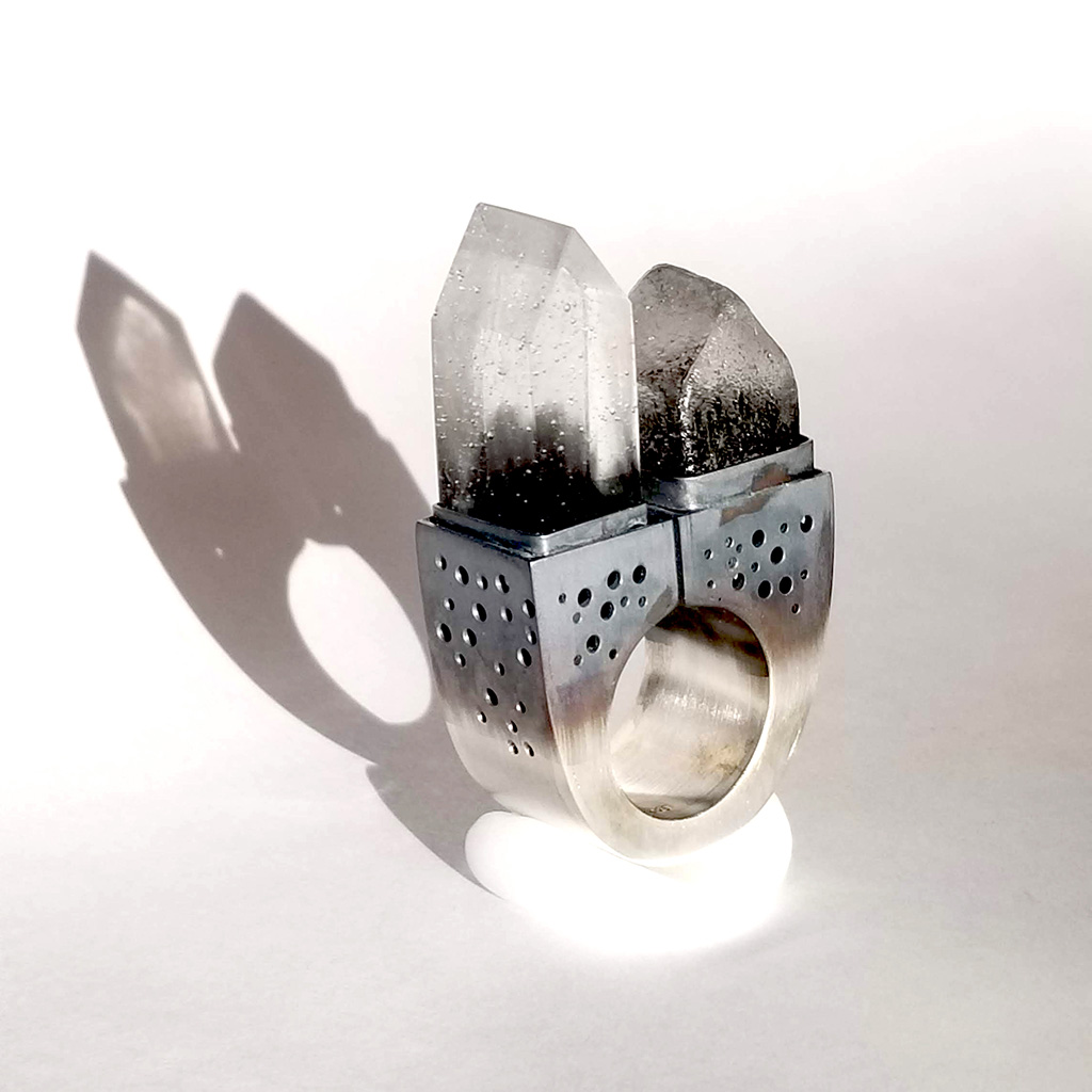 The American Dream: Fairbanks, AK is a hollow form statement ring made from silver. on the top are set two tiny glass houses