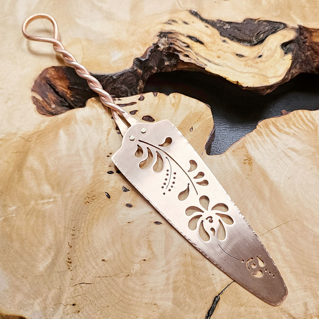 A copper cake server with pierced floral design on the blade. This one was made in 2026.