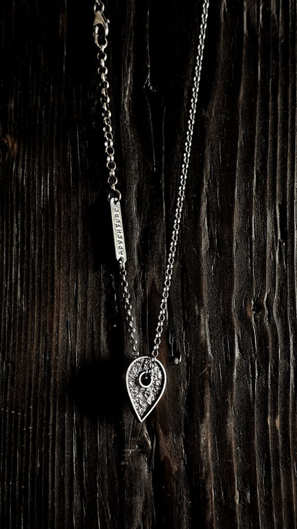 A necklace featuring a map marker planchette pendant made with reticulated silver and framed in a narrow sterling silver strip