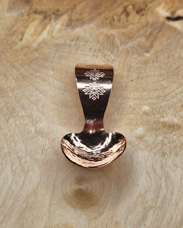 A small copper spoon stamped with three traditional eight-pointed stars