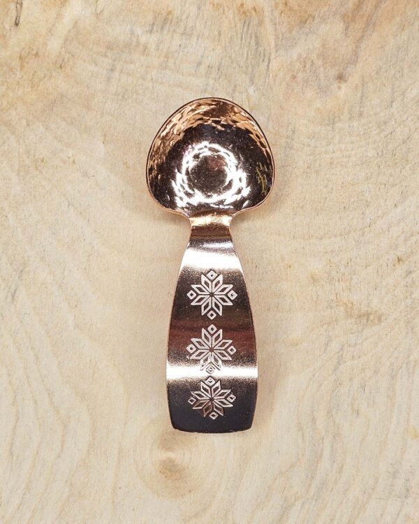 A small copper spoon stamped with three traditional eight-pointed stars