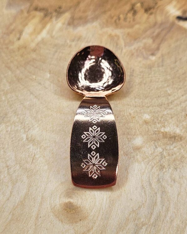 A small copper spoon stamped with three traditional eight-pointed stars