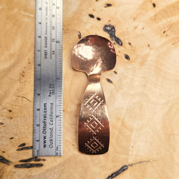 A small condiment spoon on a wood surface.
