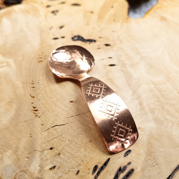 A small condiment spoon on a wood surface.