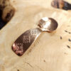 A small condiment spoon on a wood surface.