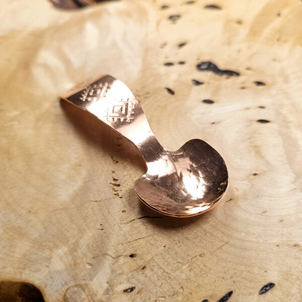 A small condiment spoon on a wood surface.