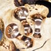 Three copper condiment spoons on a wood surface
