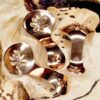 Three copper condiment spoons on a wood surface