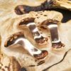 Three copper condiment spoons on a wood surface