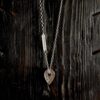 A necklace featuring a map marker planchette pendant made with reticulated silver and framed in a narrow sterling silver strip