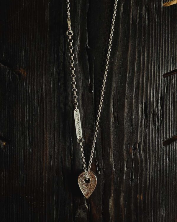 A necklace featuring a map marker planchette pendant made with reticulated silver and framed in a narrow sterling silver strip