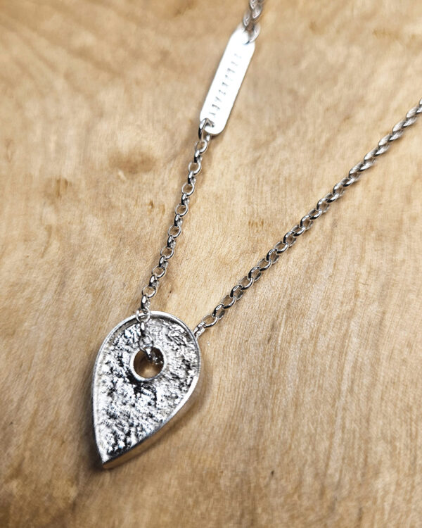 A necklace featuring a map marker planchette pendant made with reticulated silver and framed in a narrow sterling silver strip