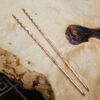 Narrow copper chopsticks on a wood surface