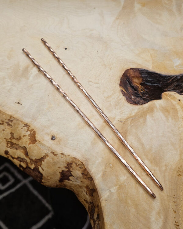 Narrow copper chopsticks on a wood surface