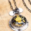 A pendant set with a yellow turquoise on a sterling silver chain sits on a wood background