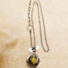 A pendant set with a yellow turquoise on a sterling silver chain sits on a wood background