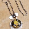 A pendant set with a yellow turquoise on a sterling silver chain sits on a wood background