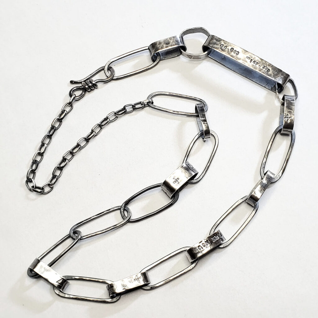 A view of the Sanctuary necklace arranged on a flat white surface